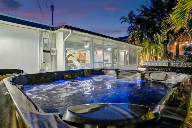 pool at dusk featuring a hot tub