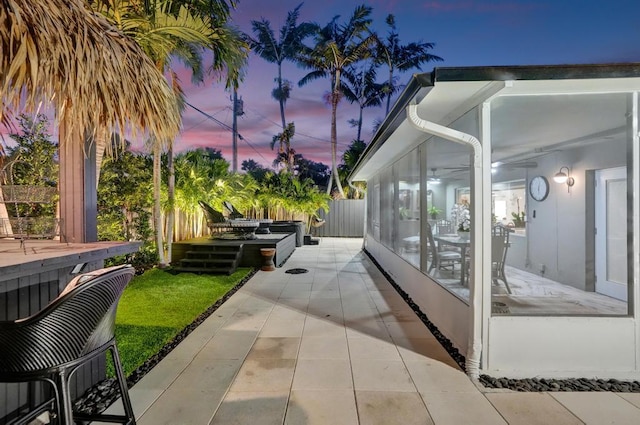 patio terrace at dusk with a sunroom and a lawn