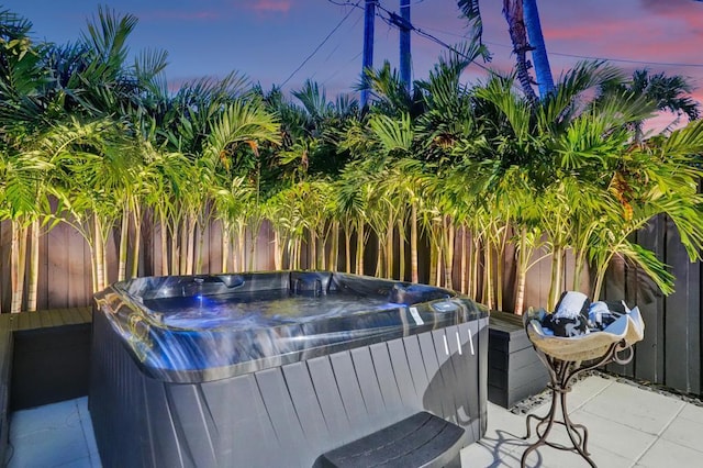 pool at dusk with a hot tub