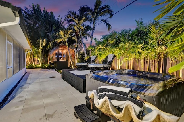 patio terrace at dusk featuring a hot tub