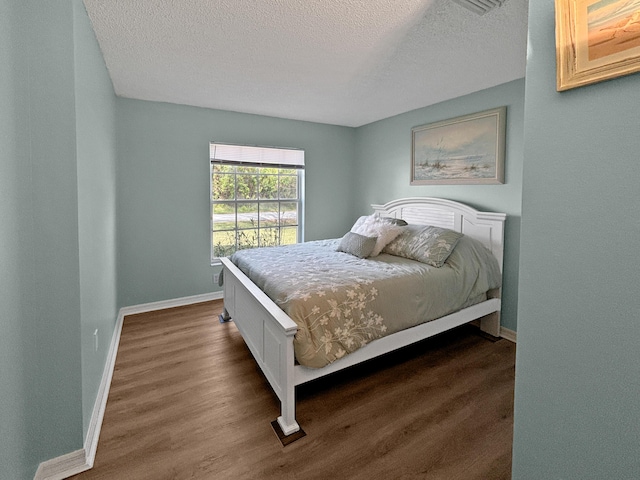 bedroom with dark wood-type flooring and a textured ceiling