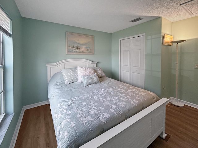 bedroom featuring dark wood-type flooring, a textured ceiling, and a closet