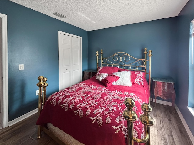 bedroom with a textured ceiling, a closet, and dark hardwood / wood-style flooring