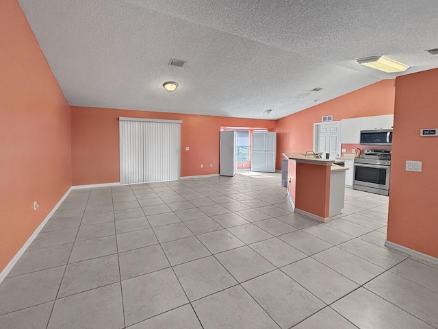 kitchen with appliances with stainless steel finishes, white cabinetry, light tile patterned floors, a kitchen bar, and lofted ceiling