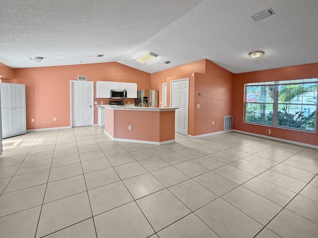 kitchen featuring vaulted ceiling, white cabinets, light tile patterned floors, a kitchen island, and stainless steel appliances