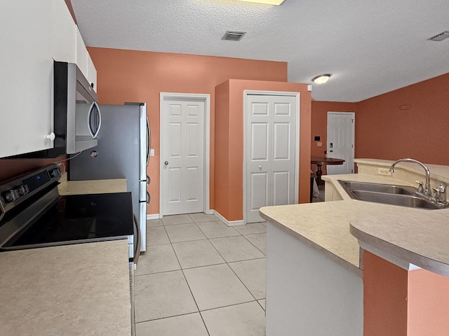 kitchen with a textured ceiling, white cabinetry, light tile patterned floors, sink, and electric range