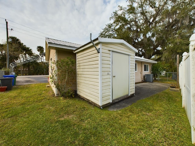 view of outdoor structure with a lawn and central AC