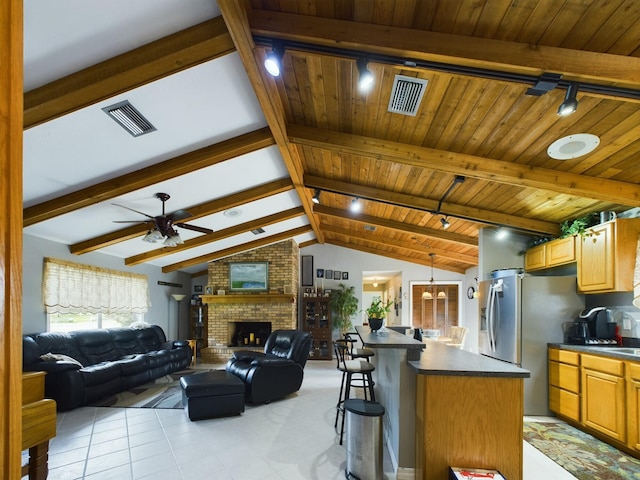 kitchen with a kitchen bar, a fireplace, wooden ceiling, ceiling fan, and lofted ceiling with beams