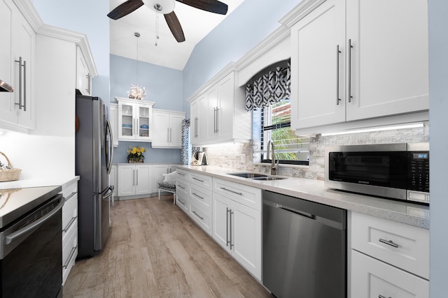 kitchen with a ceiling fan, white cabinetry, appliances with stainless steel finishes, a sink, and decorative backsplash