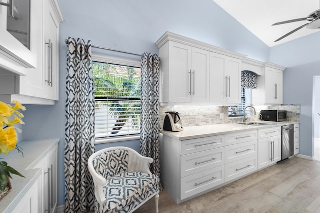kitchen featuring ceiling fan, tasteful backsplash, vaulted ceiling, a sink, and stainless steel appliances