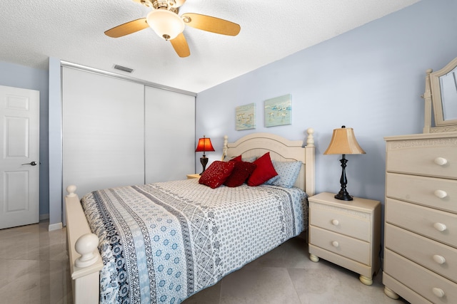 bedroom featuring ceiling fan, light tile patterned floors, a textured ceiling, a closet, and visible vents
