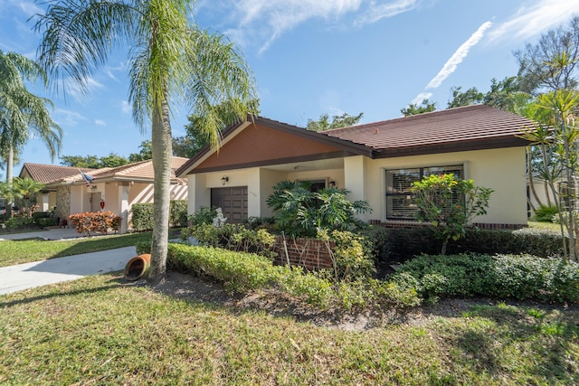 ranch-style house with a front yard, stucco siding, an attached garage, and a tile roof