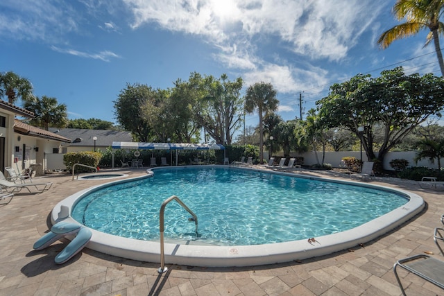 pool featuring a patio, fence, and a hot tub