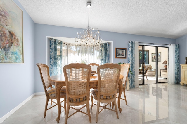 dining space featuring a textured ceiling, baseboards, an inviting chandelier, and a healthy amount of sunlight