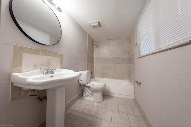 bathroom featuring toilet, tiled shower / bath, and tile patterned flooring