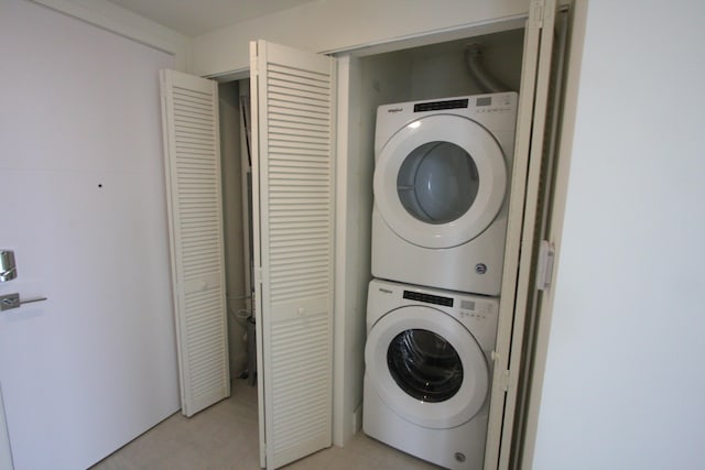 washroom with stacked washer / dryer and light tile patterned floors