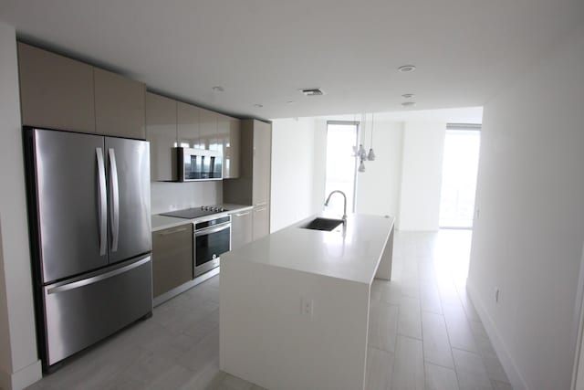 kitchen with pendant lighting, appliances with stainless steel finishes, sink, a kitchen island with sink, and expansive windows