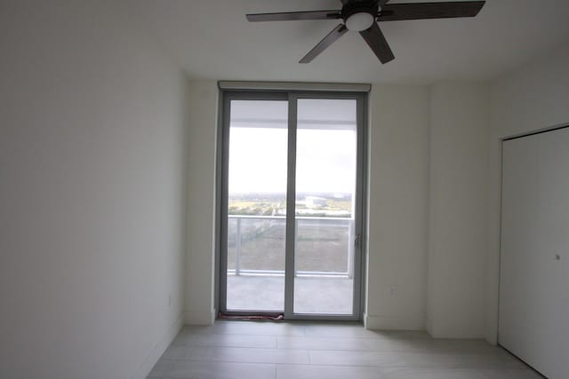 unfurnished room featuring ceiling fan and a wall of windows