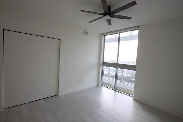 unfurnished bedroom featuring a closet, ceiling fan, and floor to ceiling windows