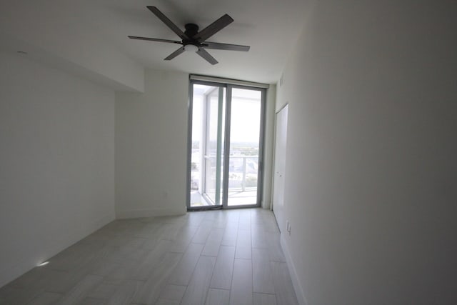 spare room featuring a wall of windows and ceiling fan