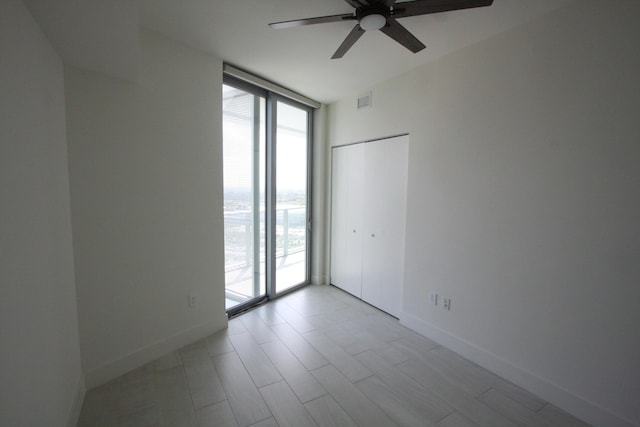 unfurnished room featuring floor to ceiling windows and ceiling fan