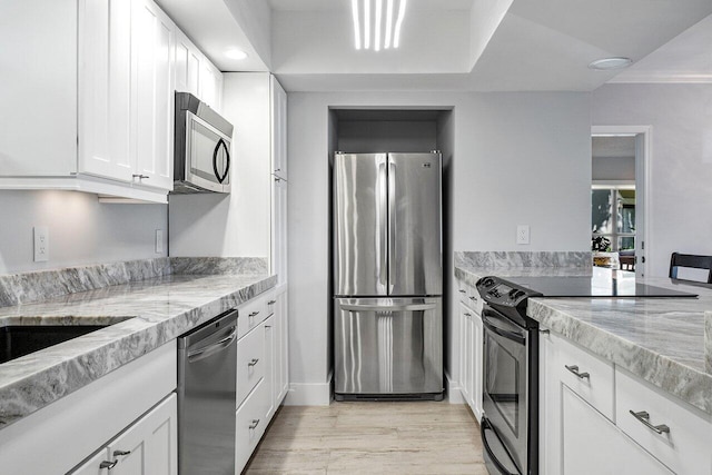 kitchen featuring appliances with stainless steel finishes, light stone countertops, light wood-type flooring, and white cabinets