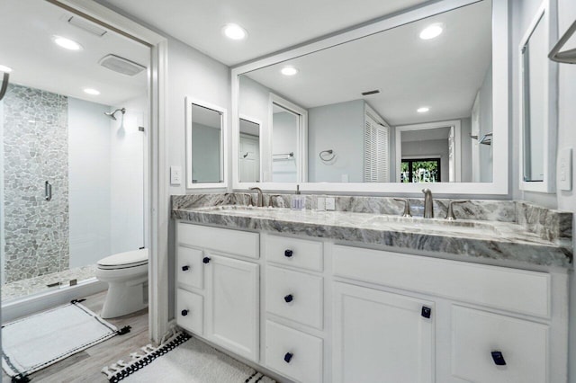 bathroom featuring a shower with door, vanity, hardwood / wood-style floors, and toilet