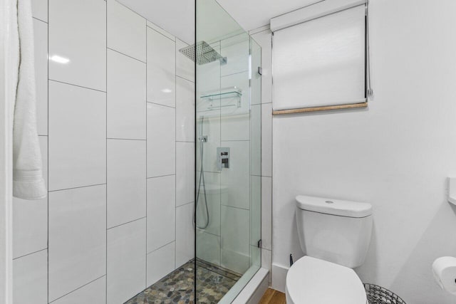 bathroom featuring a shower with door and toilet