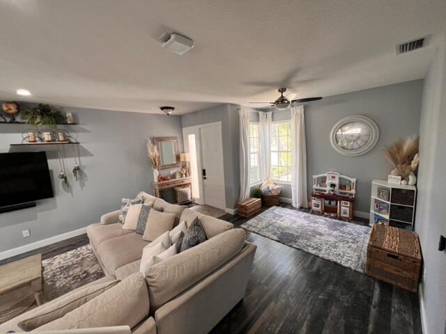 living room with dark wood-type flooring and ceiling fan