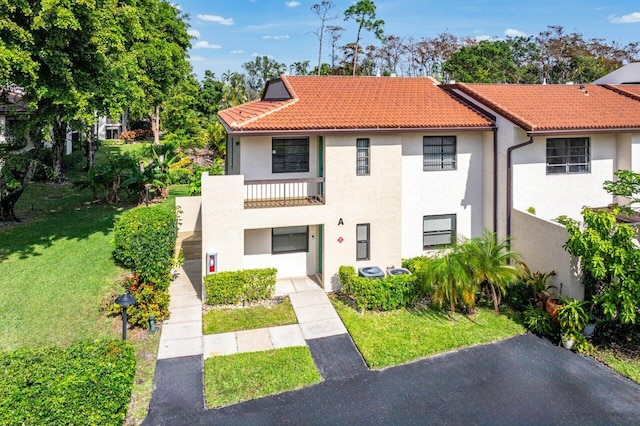 view of front of property featuring a balcony and a front lawn