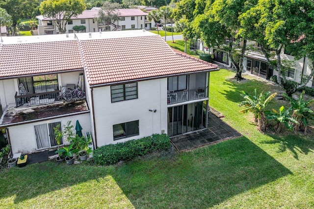 back of house featuring a balcony and a lawn