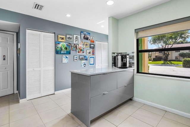 kitchen featuring light tile patterned floors, gray cabinetry, kitchen peninsula, and tasteful backsplash