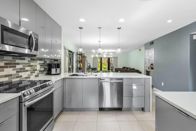 kitchen featuring gray cabinetry, sink, decorative light fixtures, kitchen peninsula, and stainless steel appliances