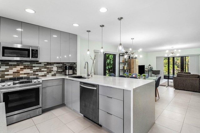 kitchen featuring kitchen peninsula, appliances with stainless steel finishes, and gray cabinetry