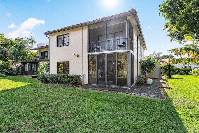 rear view of house featuring a balcony and a lawn