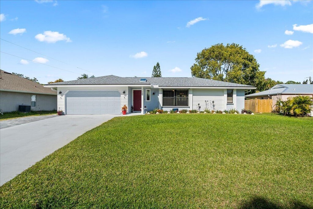 ranch-style home featuring a garage, central AC, and a front yard