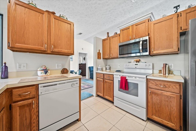 kitchen featuring appliances with stainless steel finishes, light tile patterned floors, and a textured ceiling