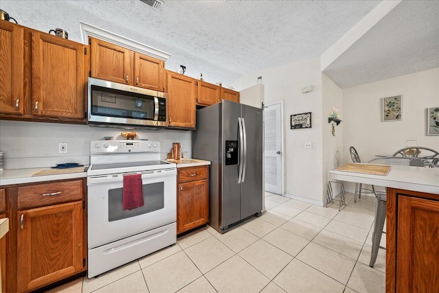 kitchen with light tile patterned flooring, stainless steel appliances, and a textured ceiling