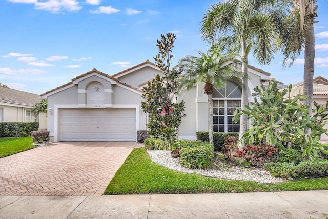 view of front of home featuring decorative driveway, a tile roof, an attached garage, and stucco siding