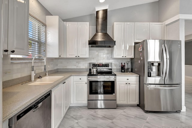 kitchen with a sink, appliances with stainless steel finishes, wall chimney exhaust hood, white cabinets, and vaulted ceiling