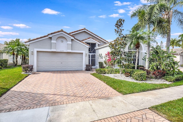 view of front of house with stucco siding, a front lawn, a garage, a tile roof, and decorative driveway