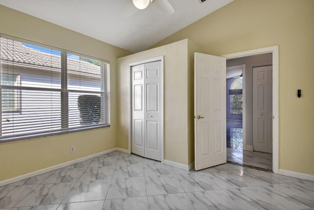 unfurnished bedroom with baseboards, lofted ceiling, a closet, marble finish floor, and a ceiling fan