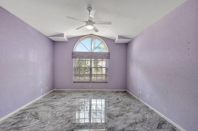 unfurnished room featuring marble finish floor, baseboards, lofted ceiling, and a textured wall