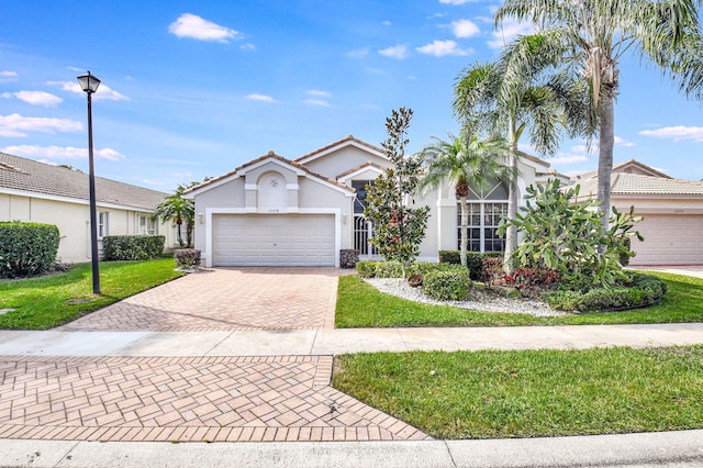 view of front of house featuring an attached garage, stucco siding, a front lawn, a tiled roof, and decorative driveway