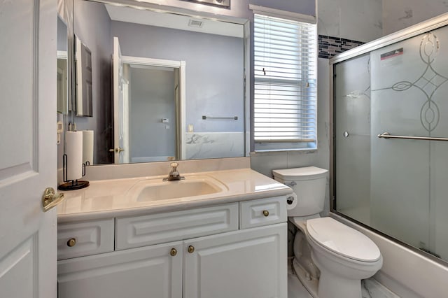 full bathroom featuring combined bath / shower with glass door, toilet, and vanity