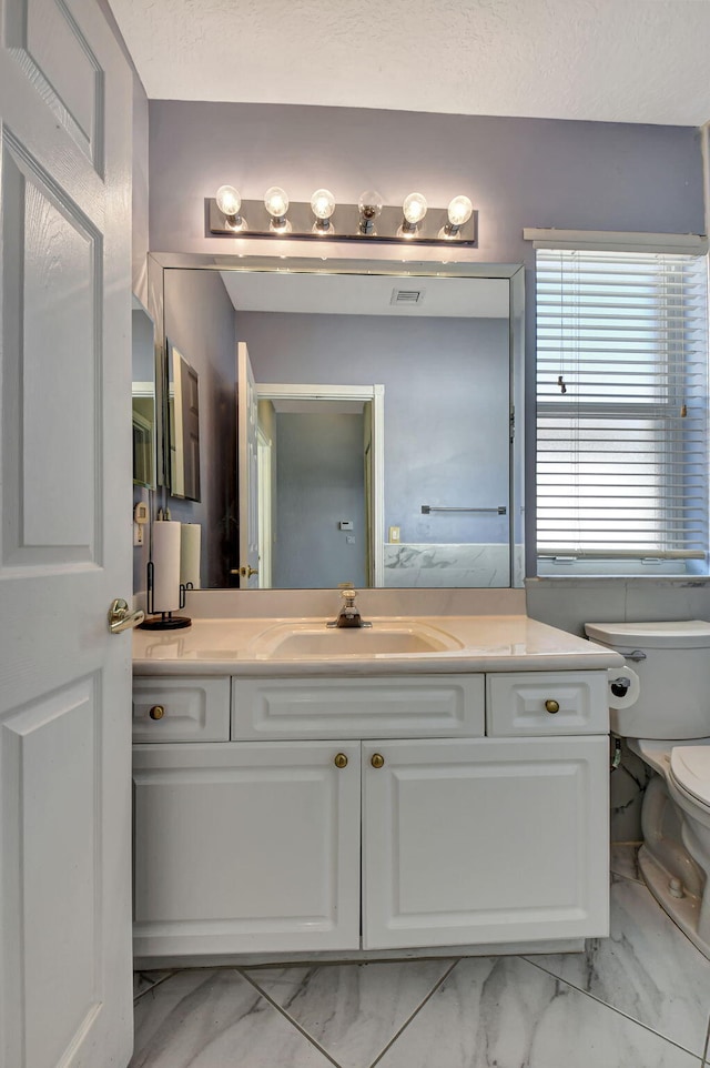 bathroom featuring visible vents, toilet, marble finish floor, and vanity