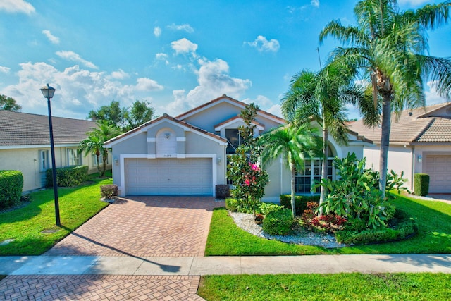 view of front of home with a front lawn, a tiled roof, stucco siding, decorative driveway, and a garage