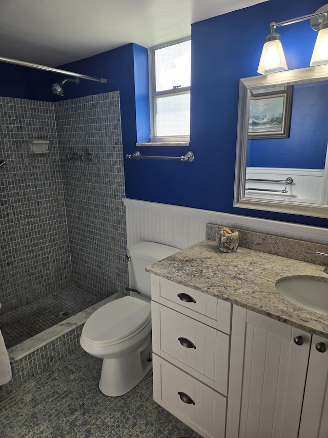 bathroom with vanity, tile patterned floors, toilet, and tiled shower