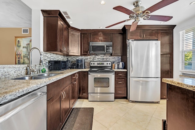 kitchen with sink, stainless steel appliances, light tile patterned floors, and light stone countertops