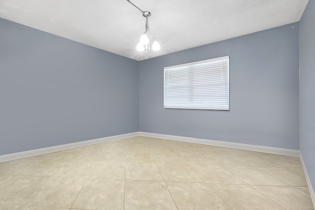 tiled empty room with an inviting chandelier